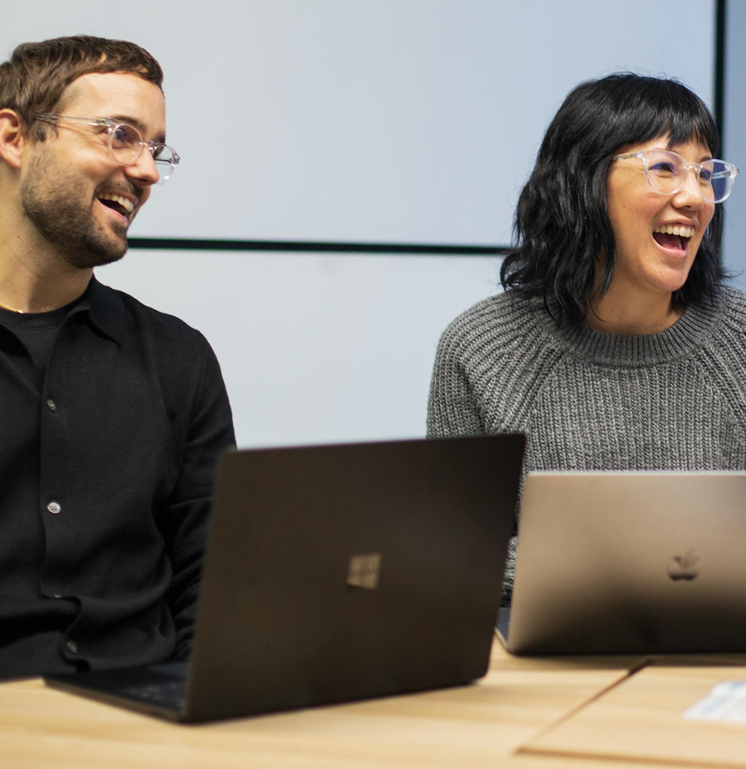 Members of the Transpire team laughing during a meeting around laptops
